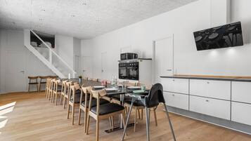 Et moderne køkken med spiseplads, træstole, indbygget ovn og en trappe.
