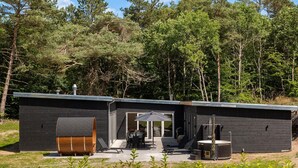 Une cabane moderne dotée d’un patio, d’une grande cuve et d’un sauna.