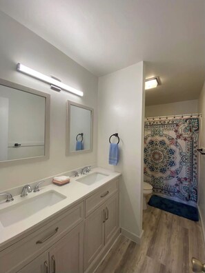Un baño con dos lavamanos, un espejo y una cortina de ducha con estampado floral.