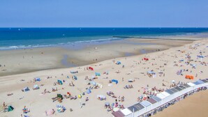 A beach with numerous sun loungers and umbrellas, a sandy shore, and a clear blue sky. - Lovely apartment in Oostende (Oostende)