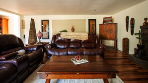 Una sala de estar con un sofá de cuero marrón, una mesa de centro de madera y un aparador con adornos.