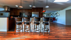 Una cocina moderna con una isla central, taburetes de bar e iluminación colgante.