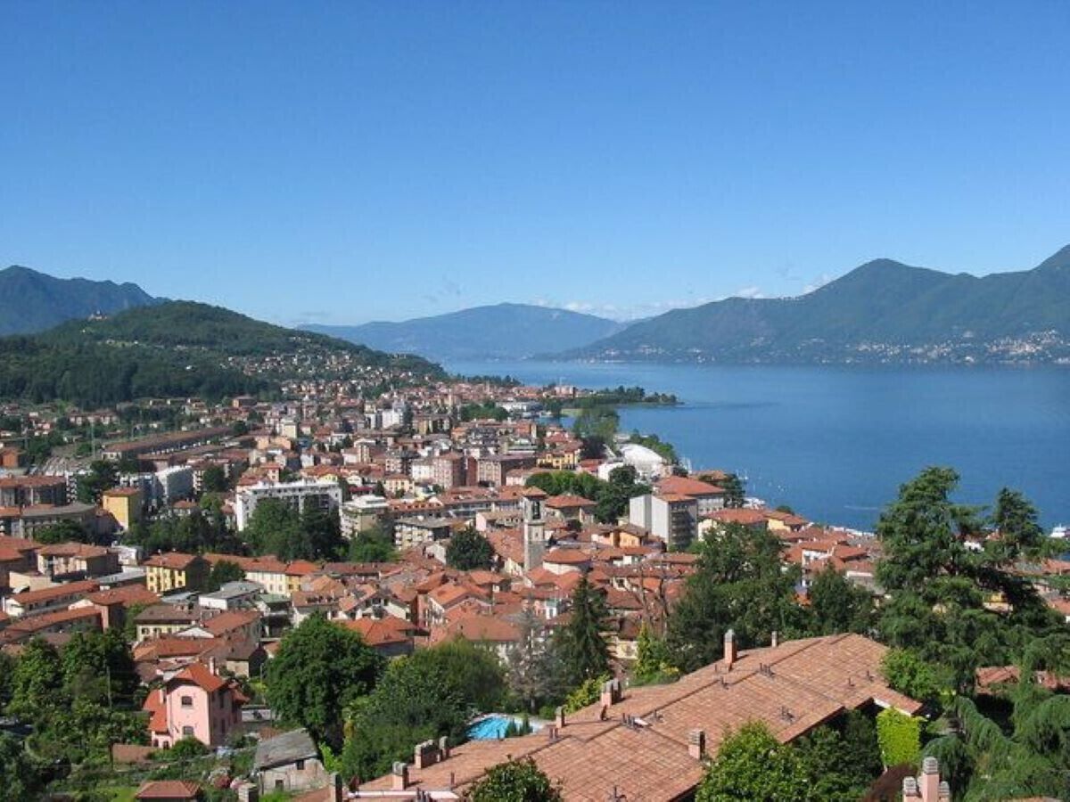Une ville côtière aux bâtiments denses, avec un ciel bleu dégagé et des montagnes en arrière-plan.