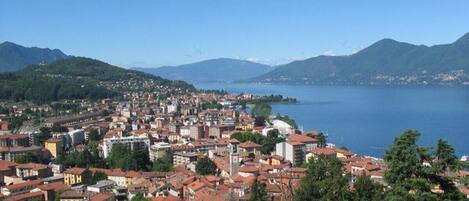 Une ville côtière aux bâtiments denses, avec un ciel bleu dégagé et des montagnes en arrière-plan.