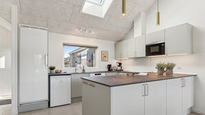Une cuisine moderne avec des meubles blancs, un îlot central et un four à micro-ondes encastré.