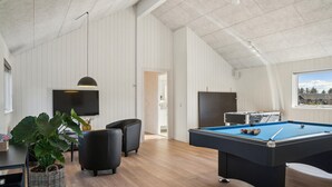 Une pièce spacieuse équipée d’une table de billard, de sièges confortables, d’un téléviseur et offrant une vue sur l’extérieur.