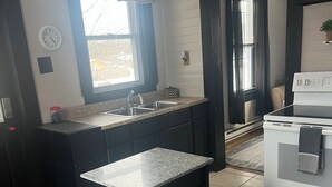 A kitchen with a granite countertop, a sink, a stove, and a 'Welcome' sign. - The Sasquatch Hideaway: Private 1BR Adventure Loft (Fayetteville)