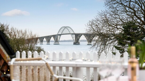 Une vue d’un pont enjambant une étendue d’eau, avec une clôture blanche au premier plan.