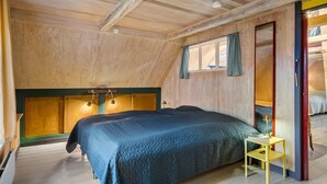 Une chambre à coucher avec un lit, des lampes de chevet, une fenêtre avec des rideaux et une petite table.