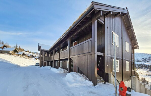 Ein großes Holzhaus mit mehreren Etagen und einem steilen Dach, umgeben von Schnee.