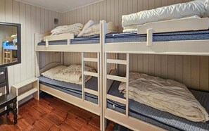 Ein Schlafraum mit Etagenbetten, Holzboden, einem kleinen Schreibtisch und einem Spiegel.