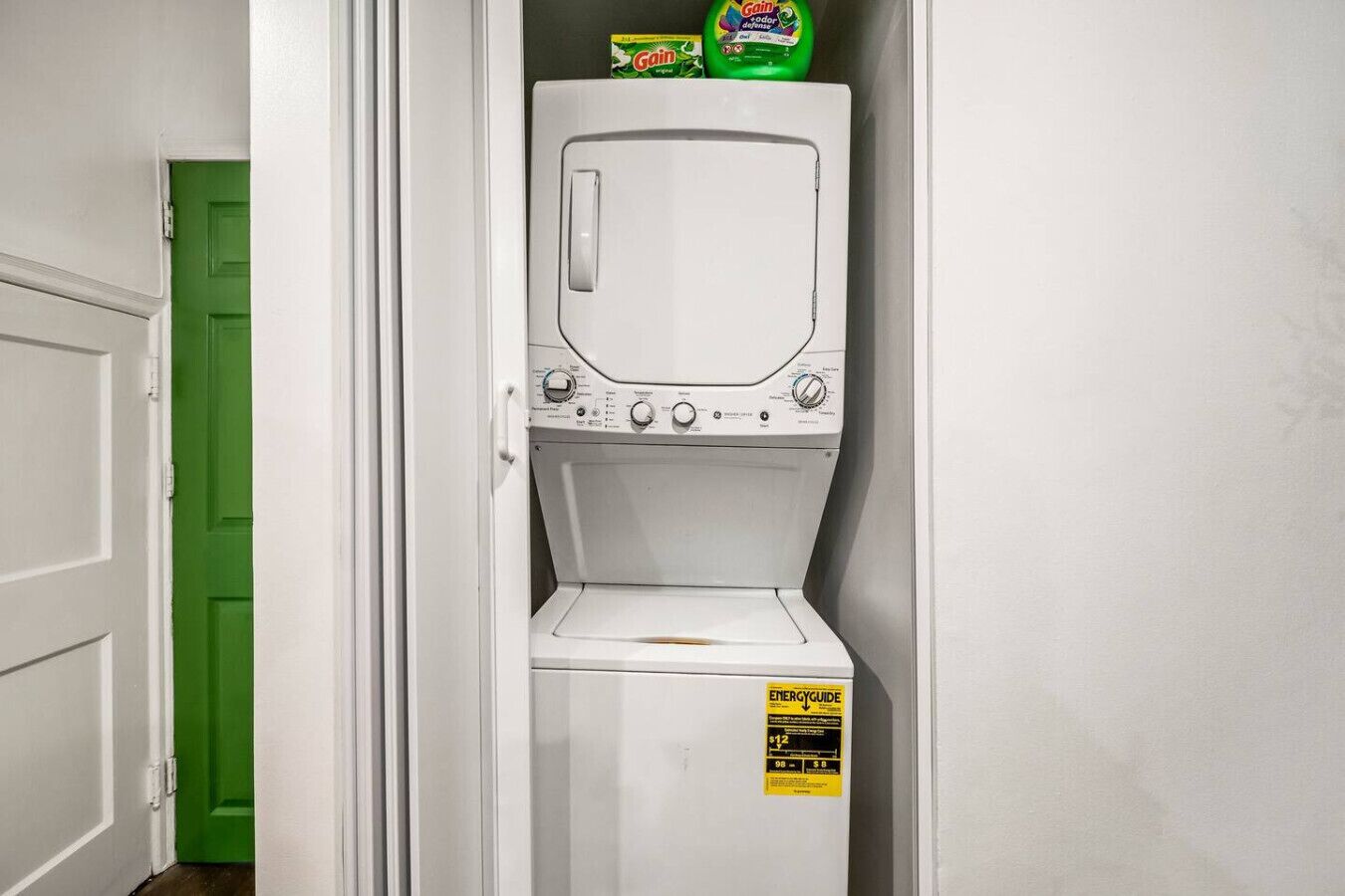 A compact washer and dryer unit with a green door in the background.