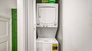 A compact washer and dryer unit with a green door in the background.