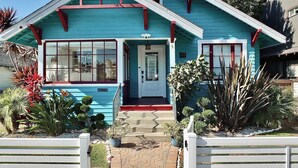 Una casa con fachada azul, un porche delantero y el número 233 en la puerta.
