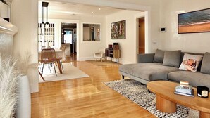 Un salón amplio con un sofá gris, una mesa de centro de madera y un comedor con mesa y sillas.