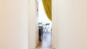 A narrow hallway with a wooden floor leading to a dining area with a table and chairs. - L Angolo do core (Naples)