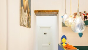 A hallway with patterned floor tiles, a painting on the wall, and a door at the end. - L Angolo do core (Naples)