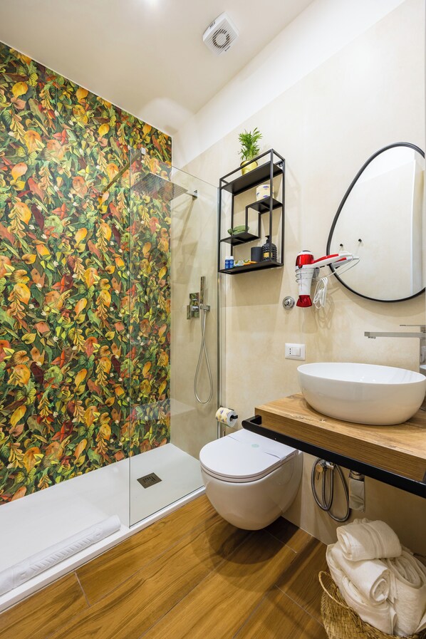 Un baño moderno con cabina de ducha de vidrio, un lavabo blanco y un mueble de tocador de madera.