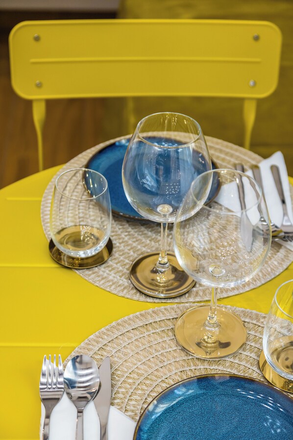 A table set with blue and clear wine glasses, a gold plate, and silverware on a yellow tablecloth. - L Angolo do core (Naples)
