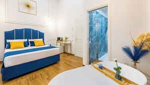 A modern bedroom with a large bed, a small table with a coffee maker, and a bathroom with a white sink and decorative plants. - L Angolo do core (Naples)