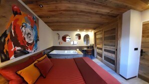 Ein Schlafzimmer mit einem großen Bett, einem Gemälde an der Wand, einer Badewanne und einer Holzbalkendecke.