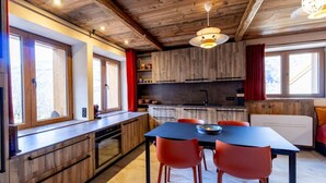 Eine moderne Küche mit Holzschränken, einer schwarzen Arbeitsplatte und einem Essbereich mit roten Stühlen.