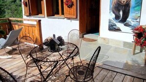 Eine Holzhütte mit Balkon, Sitzgelegenheit im Freien und einem Bärenbild.