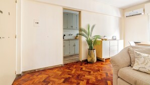 Ein modernes Wohnzimmer mit Fischgrätparkett, einem beigefarbenen Sofa und einem Topf mit Pflanze.