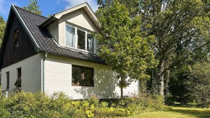 Et etagers hus med saddeltag, hvid facade og en veranda.