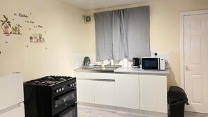 A compact kitchen with a gas stove, microwave, and a small sink. - Kisobi Home Bedroom 1 (Kingston upon Hull)
