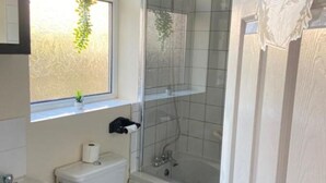 A bathroom with a toilet, sink, and glass-enclosed shower. - Kisobi Home Bedroom 1 (Kingston upon Hull)