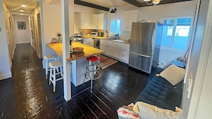 A modern kitchen with a central island, stainless steel appliances, and white cabinetry. - Cozy, private & charming 3bd/2ba cottage in a magical little village by the Sea (Newport Beach)