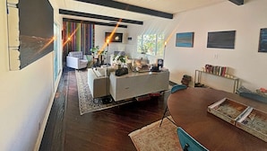 A modern living room with a fireplace, a dining area, and a view of the outdoors. - Cozy, private & charming 3bd/2ba cottage in a magical little village by the Sea (Newport Beach)