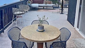 A covered outdoor patio with a round table and four chairs, a sofa, and a potted plant. - Cozy, private & charming 3bd/2ba cottage in a magical little village by the Sea (Newport Beach)