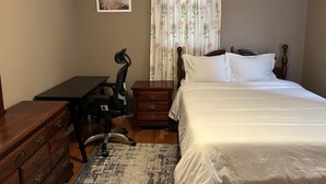 Une chambre à coucher comprenant un lit, un bureau, une chaise, une commode et une table de chevet.