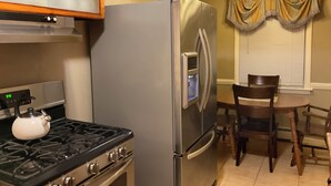 Une cuisine équipée d’un réfrigérateur en acier inoxydable, d’une cuisinière à gaz et d’une table à manger avec des chaises.