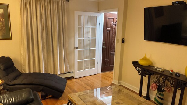 Un salon avec un canapé en cuir, une table basse en verre et un téléviseur à écran plat fixé au mur.