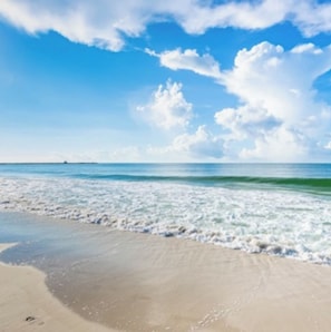 Een strand met heldere lucht en golven.