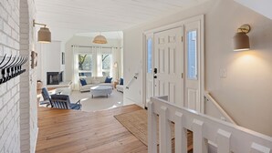 A spacious living area with a fireplace, a staircase, and a view of the outdoors.