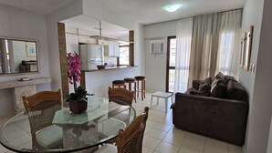 A dining area with a glass table and chairs, a sofa, and a potted plant. - Sua Casa no Rio Ipanema 2Qts com Garagem (Rio de Janeiro)