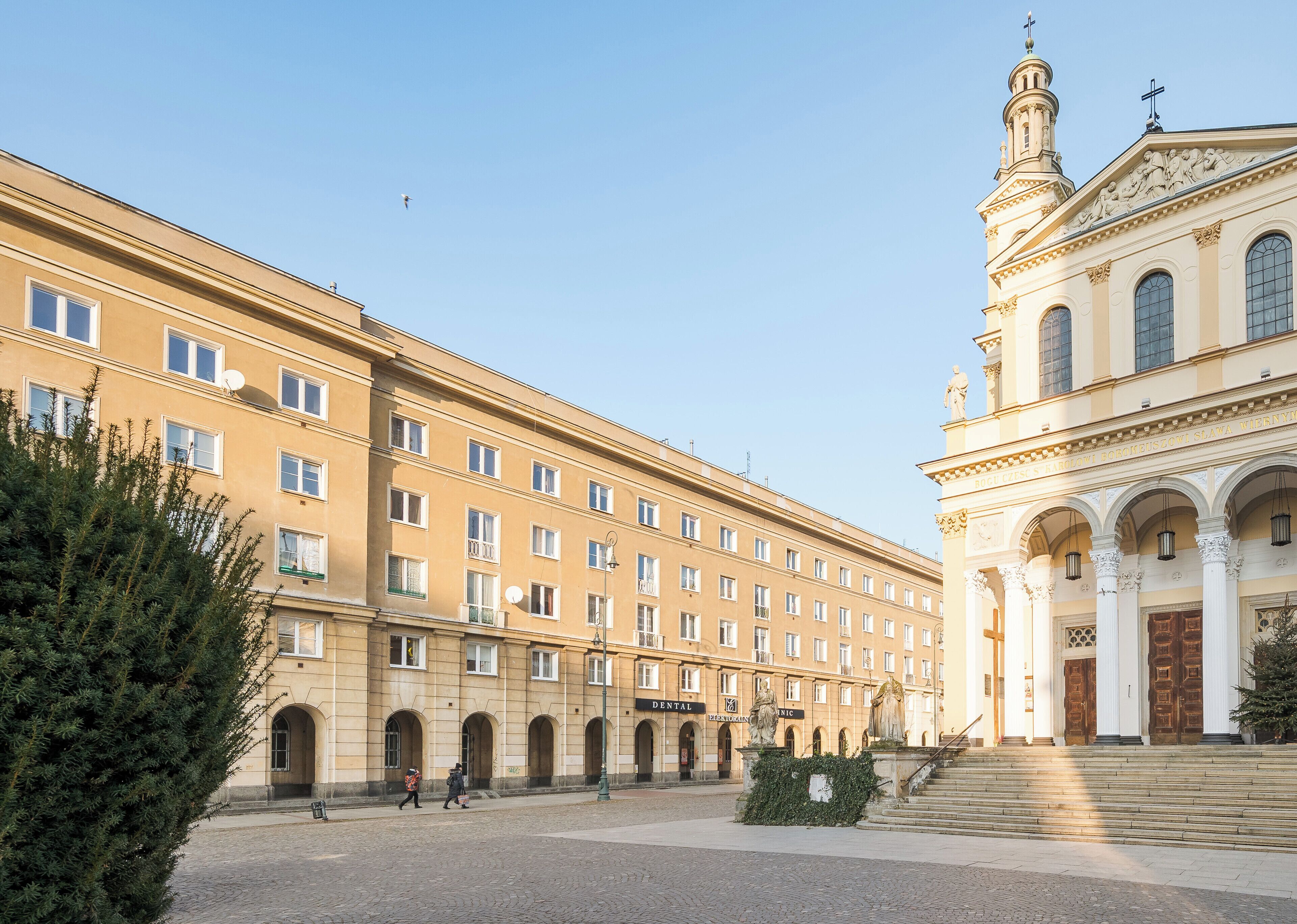 Ein historisches Gebäude mit einer klassischen Fassade, zahlreichen Fenstern und einer zentralen Treppe, die zu einem Eingang führt.