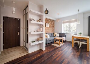 A modern living room with a sofa, wooden coffee table, and built-in shelves. - Elektoralna Charming Apartment (Warszawa)