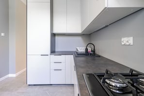 Una cocina moderna con armarios blancos, encimera negra, estufa a gas y un lavabo con grifo.