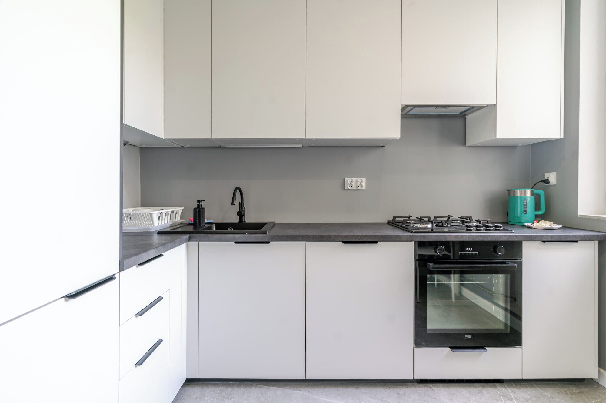A modern kitchen with white cabinets, a black faucet, a gas stove, and a built-in oven.