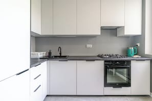 A modern kitchen with white cabinets, a black faucet, a gas stove, and a built-in oven.