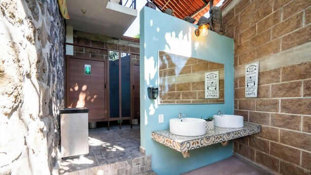 A bathroom with a blue wall, two sinks, a mirror, and a trash bin. - Cozy House with Pool and 3 Bedrooms (Yautepec)