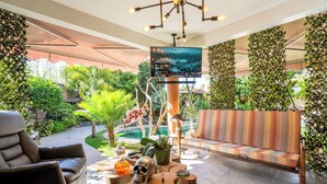 A modern lounge area with a sofa, armchair, and a TV screen displaying a landscape. - Cozy House with Pool and 3 Bedrooms (Yautepec)