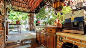 A kitchen with a brick wall, a microwave, and a refrigerator. - Cozy House with Pool and 3 Bedrooms (Yautepec)