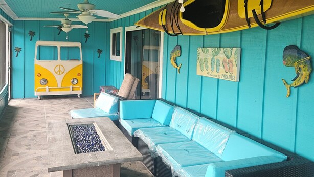 A room with a blue and yellow van, a ceiling fan, and a sign that says "Welcome to Paradise". - St. Lucie Breezes 2 (Palm City)