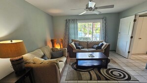A living room with two sofas, a coffee table, a lamp, and a ceiling fan. - St. Lucie Breezes 2 (Palm City)